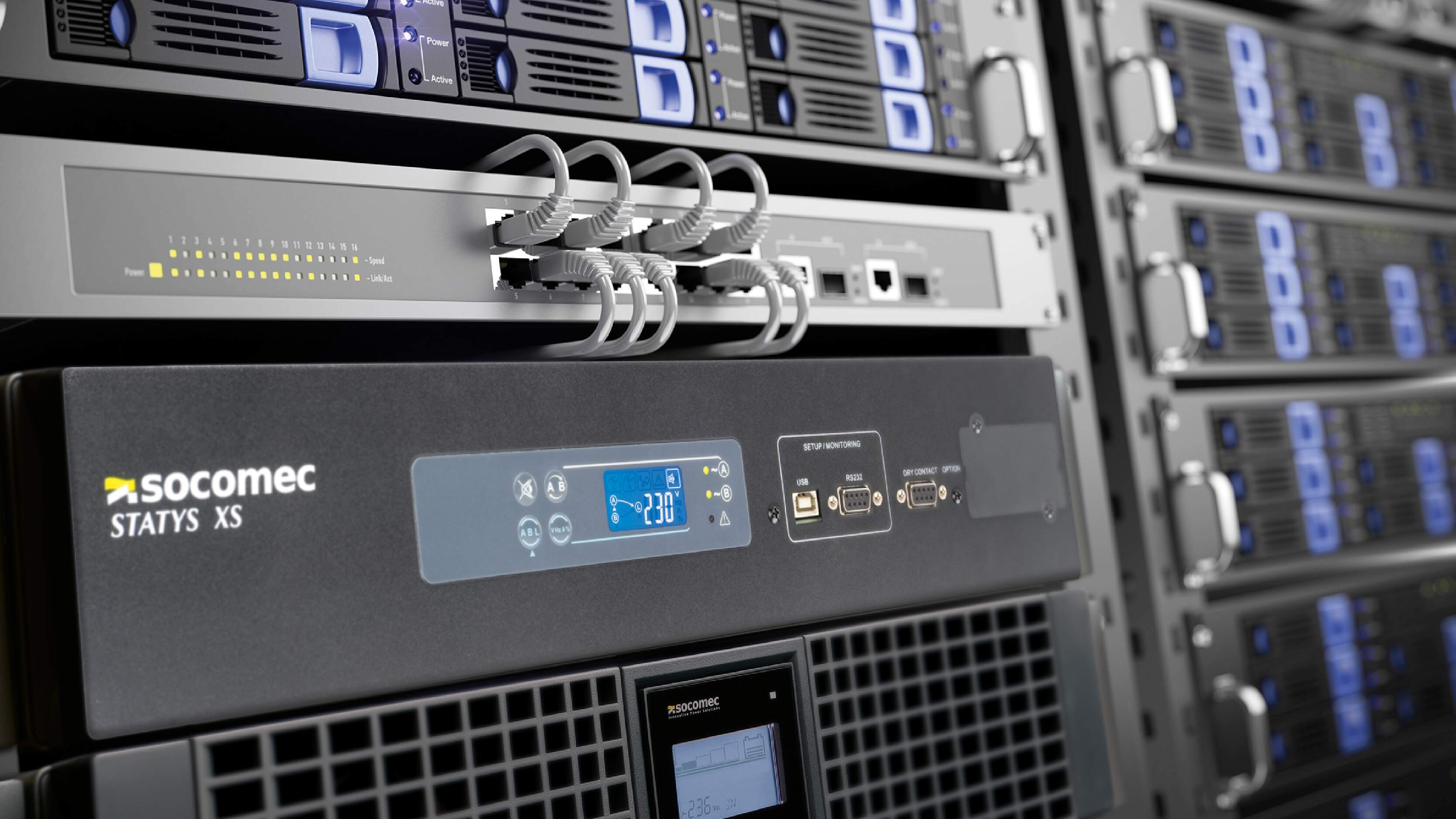 Close-up of a server rack with network cables and a Socomec STATYS XS power device, showing digital displays and connection ports.