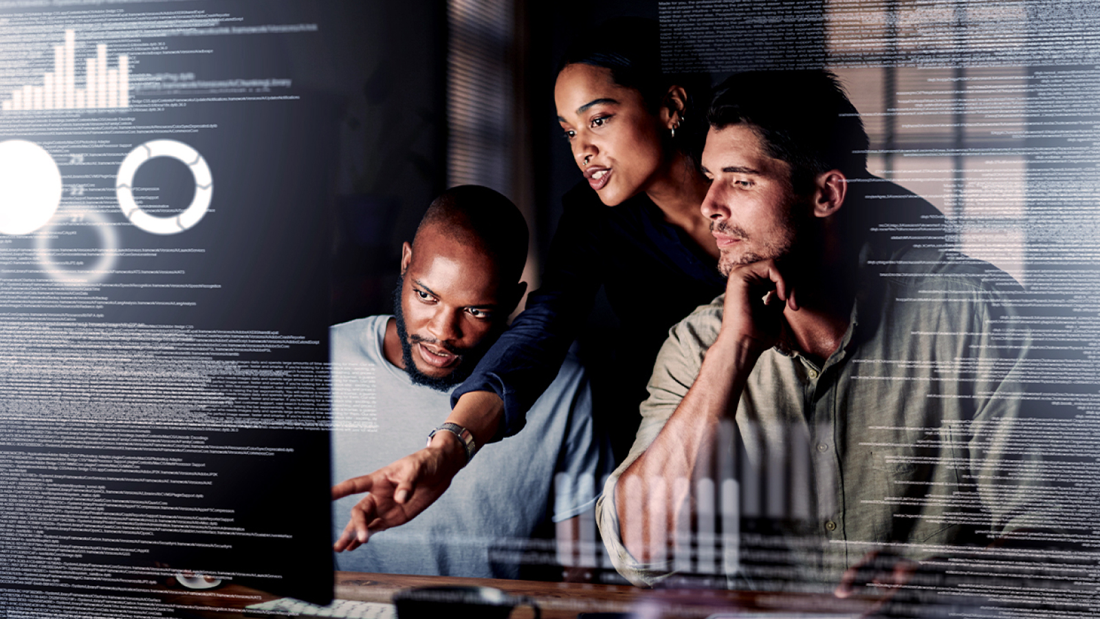 A team of three collaborating in front of a computer screen displaying digital analytics and data visualization.
