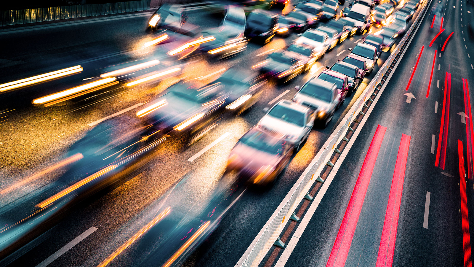 A motion-blurred image of heavy traffic on a highway at night, with streaks of red and yellow lights illustrating speed and congestion.