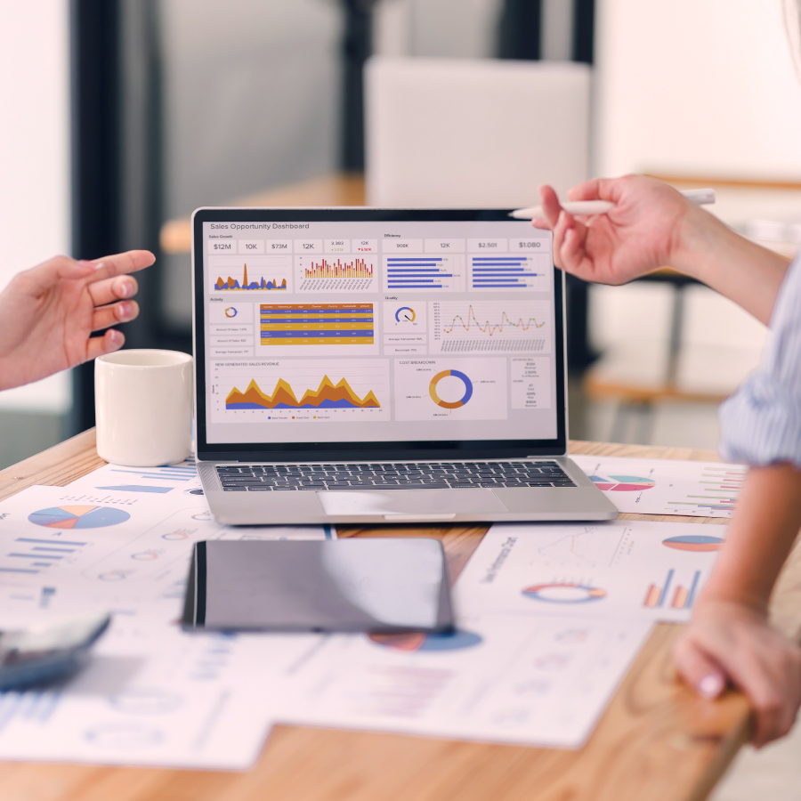 laptop on a table with scattered papers, collaborating on a project.