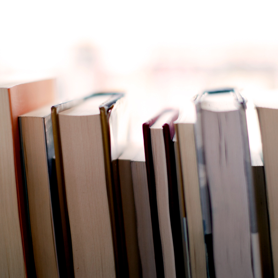 A neatly arranged stack of books resting on a wooden table, showcasing various colors and sizes.