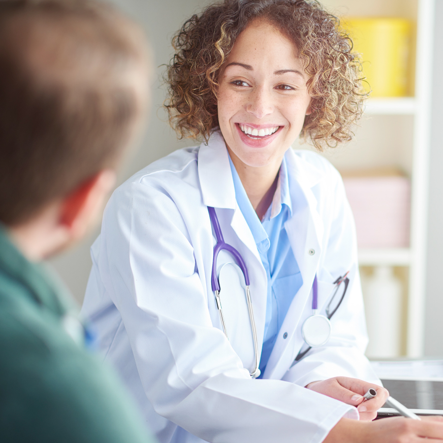 A woman speaks with a man in a doctor's office, highlighting a patient-doctor interaction.