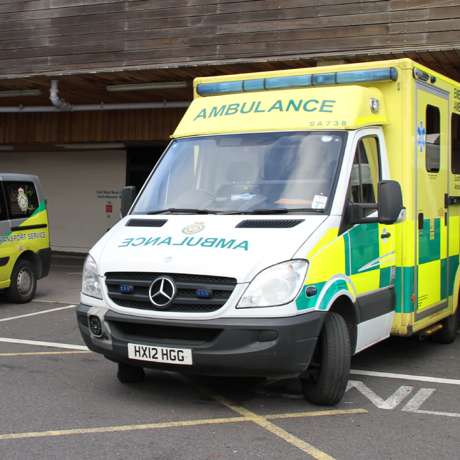 A yellow ambulance parked, showcasing its bright color against the surrounding environment.