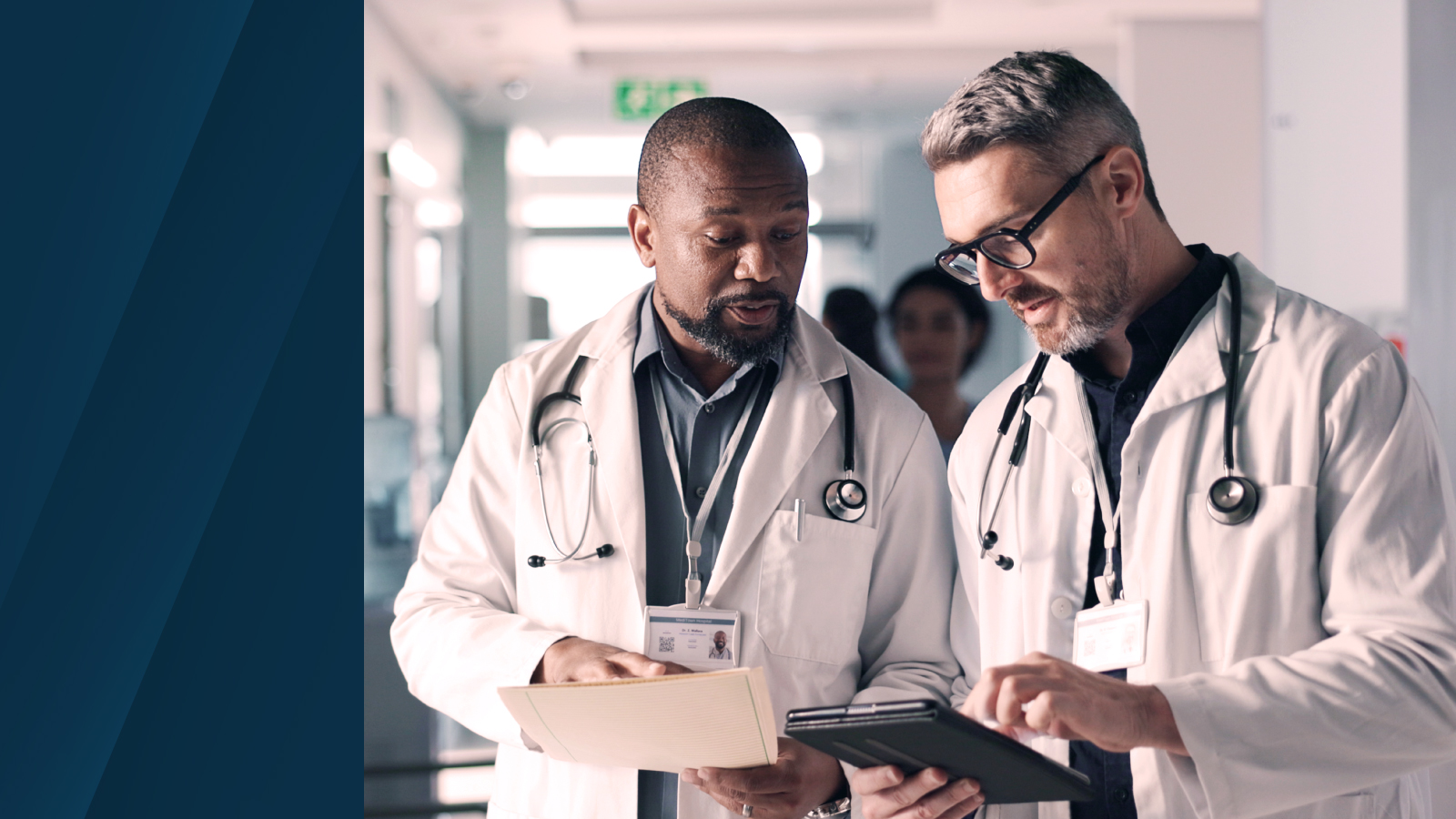 Two doctors in lab coats and stethoscopes reviewing patient data on a tablet in a hospital setting, representing collaboration in healthcare financial planning.