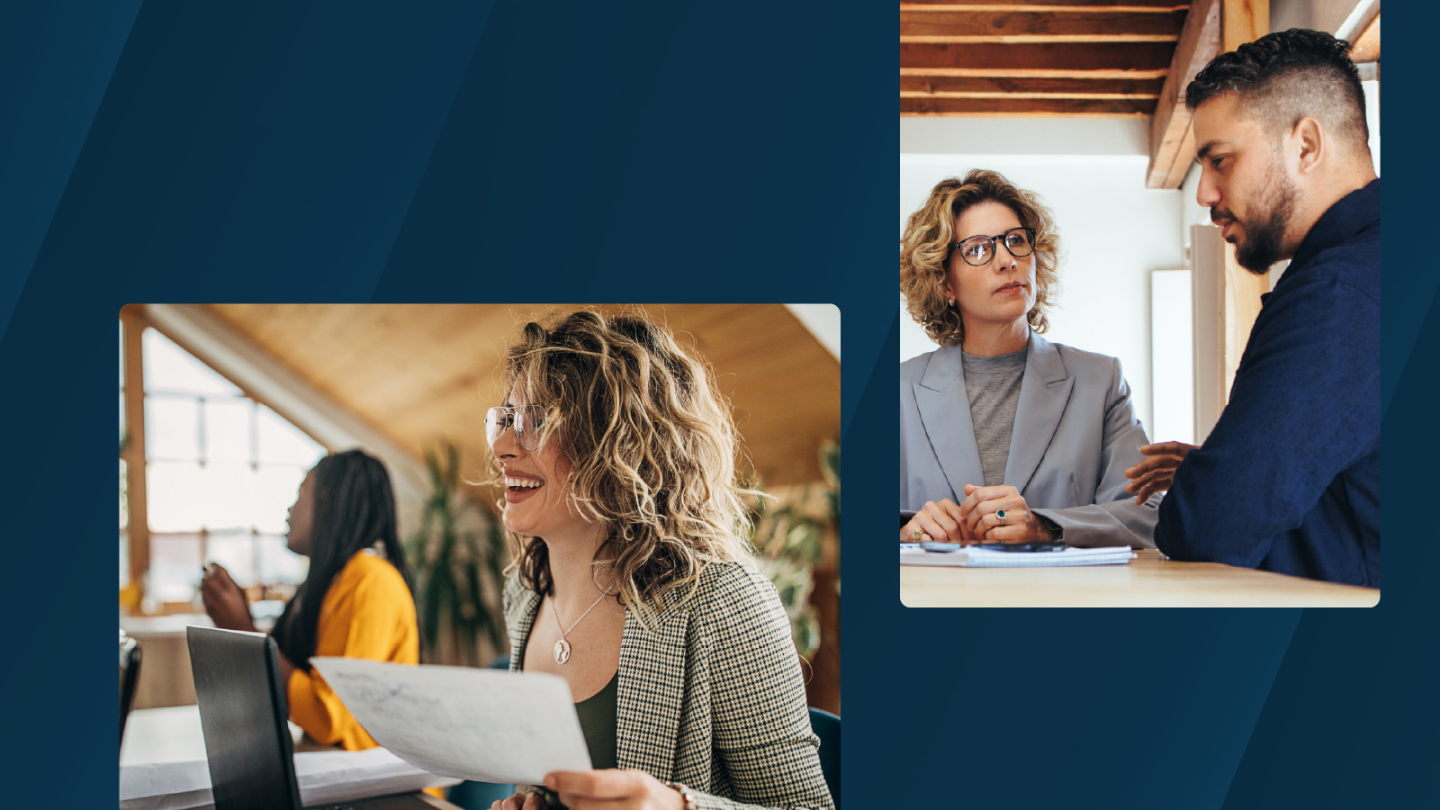 A smiling woman holds a document while working at a desk in a bright office, with another colleague seated nearby in the background.
