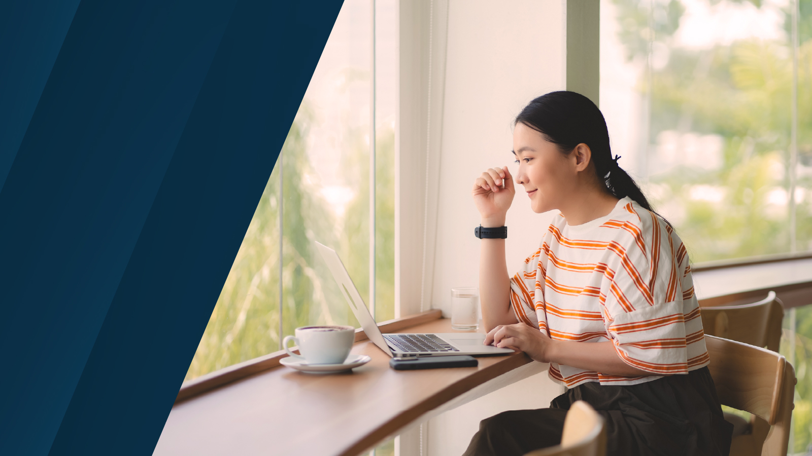 Woman working on a laptop by a window. A casual scene of a woman smiling while focused on her screen, with a coffee cup and natural light in a peaceful workspace.