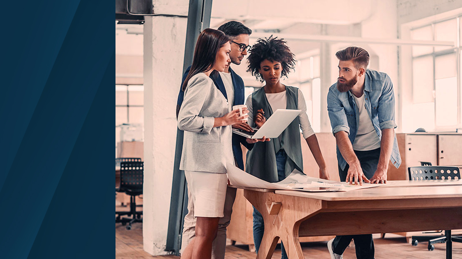 Four professionals collaborate around a wooden table with documents and a laptop, inside a bright modern office.