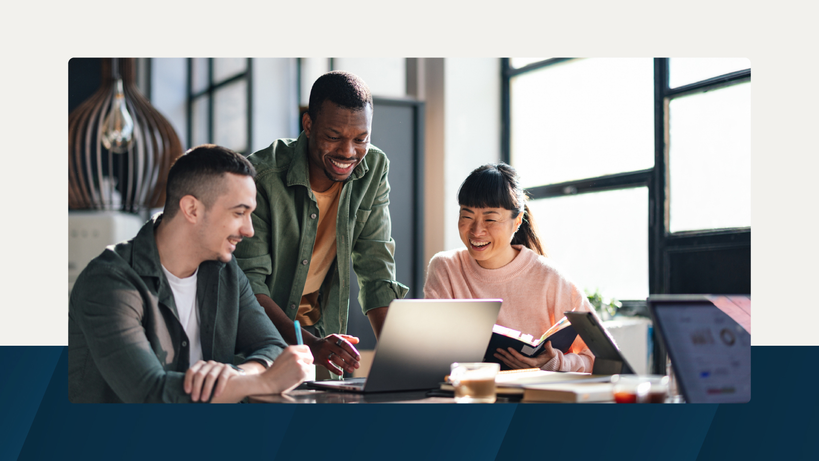 A diverse group of individuals collaborating on a laptop, engaged in discussion and teamwork in a modern workspace.