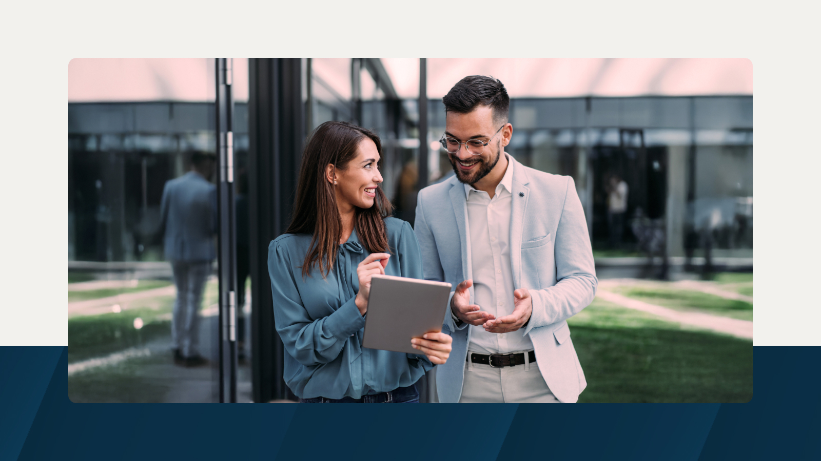 Two professionals smiling and reviewing a tablet together in an outdoor office environment, symbolizing collaboration and strategic workforce planning.
