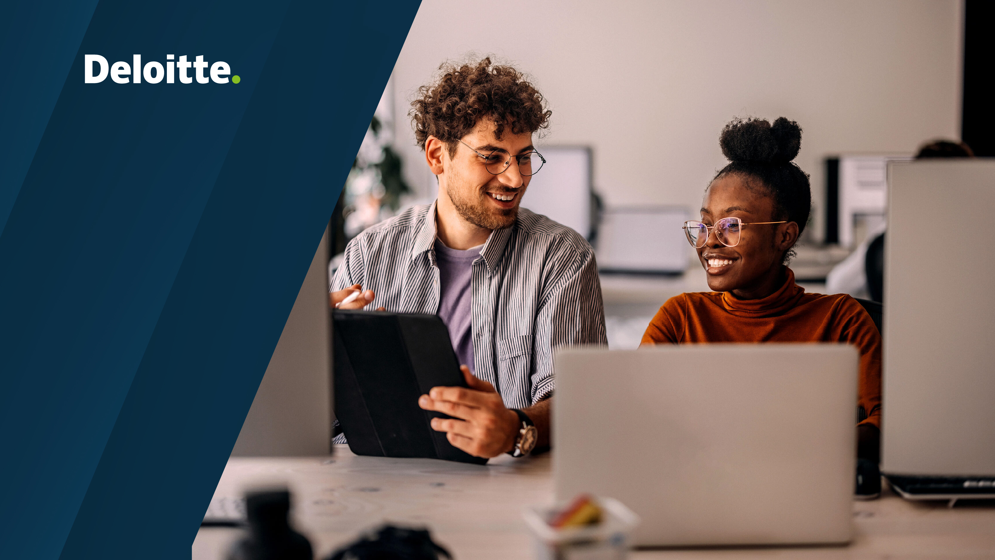 Deloitte displayed on a blue background. A man and woman are seated beside each other, smiling while working on a tablet and laptop.