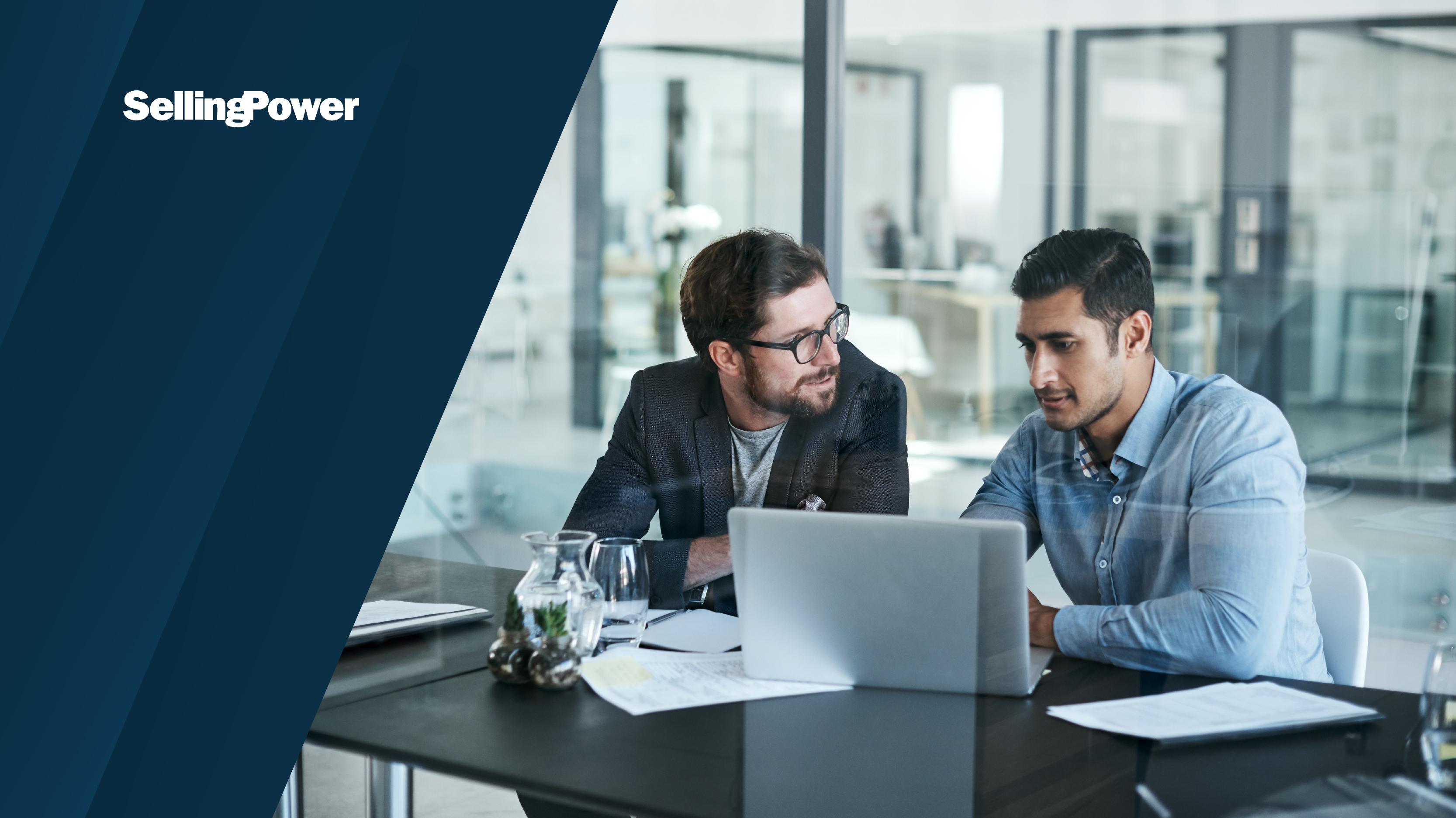 A professional business setting with two men working together at a laptop, with the Selling Power logo over a dark blue background.