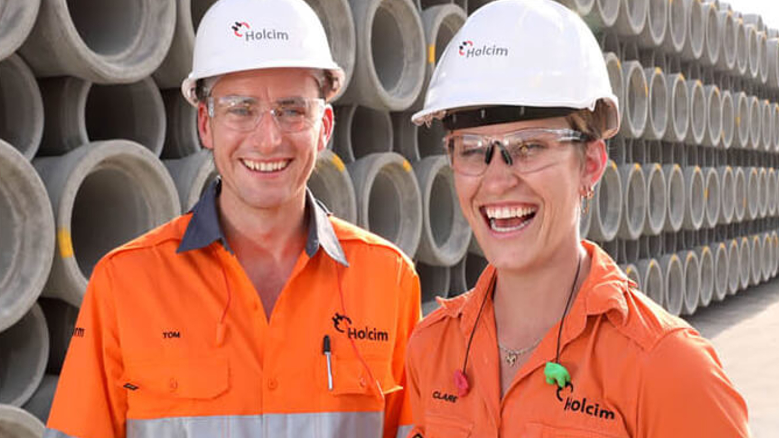 Holcim Anz workers in orange jumpsuits and white hard hats.